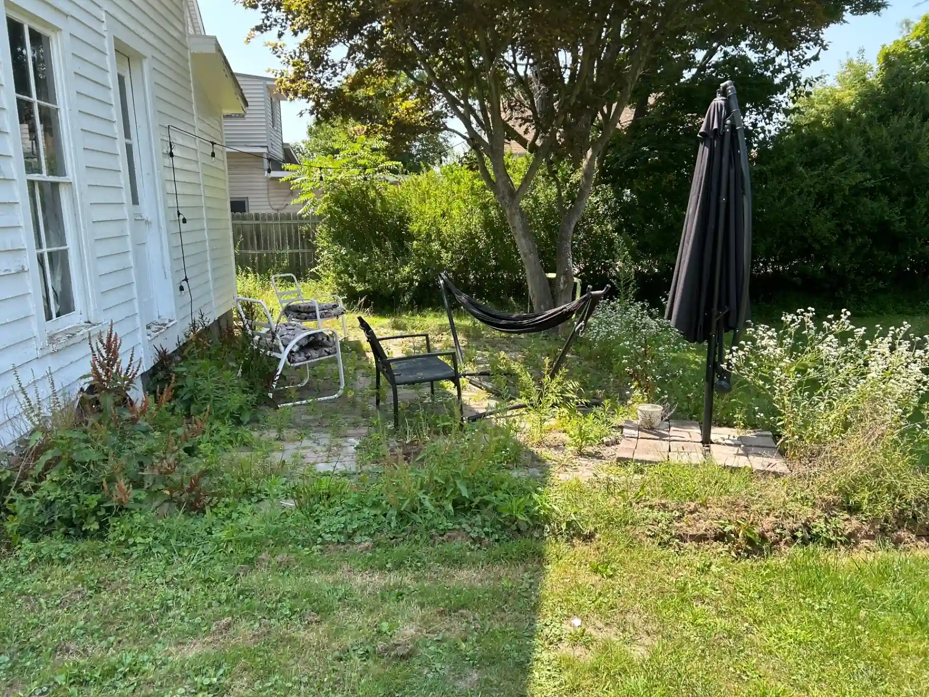 Before patio transformation - overgrown weedy patio